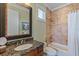 Cozy bathroom with granite countertop, a framed mirror, and tiled tub and shower at 9 Peekins Cove Dr, Boca Grande, FL 33921