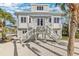 Charming home with a double staircase leading to the front entrance, set against a backdrop of swaying palm trees at 9 Peekins Cove Dr, Boca Grande, FL 33921