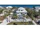 Beautiful two-story beach house featuring a white exterior, staircase, and a meticulously landscaped yard with palm trees at 9 Peekins Cove Dr, Boca Grande, FL 33921