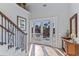 Bright foyer showcasing tile floors, staircase with ornate railing, French doors opening to a balcony, and stylish furnishings at 9 Peekins Cove Dr, Boca Grande, FL 33921