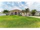 A single-story home featuring a lush lawn, palm trees, and an attached two-car garage at 10640 Ayear Rd, Port Charlotte, FL 33981