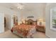 Comfortable bedroom featuring a ceiling fan, two bedside lamps, a floral bedspread, and outside views at 1104 Yosemite Dr, Englewood, FL 34223