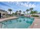 A community pool featuring clear blue water and ample seating surrounded by palm trees at 1104 Yosemite Dr, Englewood, FL 34223