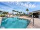 A community pool featuring clear blue water and ample seating surrounded by palm trees at 1104 Yosemite Dr, Englewood, FL 34223