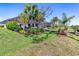 Expansive backyard with lush green lawn, tropical plants, and a view of the screened-in lanai at 14564 Gaspar Loop, Port Charlotte, FL 33981