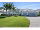 Well-maintained home with a spacious lawn, mature landscaping, and a paver driveway leading to a two-car garage at 14564 Gaspar Loop, Port Charlotte, FL 33981