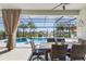 Covered patio with dining table and chairs overlooking a beautiful pool and landscaping at 14564 Gaspar Loop, Port Charlotte, FL 33981