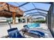 Screened-in pool area with lounge seating, a built-in bar, and a tropical-themed tiki umbrella at 14564 Gaspar Loop, Port Charlotte, FL 33981