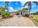 Charming home featuring a brick driveway, a tile roof, and beautiful landscaping with flowers and palm trees at 14810 Ingraham Blvd, Port Charlotte, FL 33981