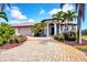 Attractive home showcasing a brick driveway, a tile roof, and carefully manicured landscaping with palm trees at 14810 Ingraham Blvd, Port Charlotte, FL 33981