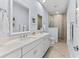 Bright bathroom featuring double vanity with white cabinets, granite counters, and a tiled shower with pebble accents at 15380 Alsask Cir, Port Charlotte, FL 33981