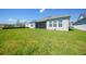 View of a home's spacious backyard with lush green lawn and a screened lanai at 1607 Laurel Brook Ln, Port Charlotte, FL 33953