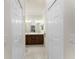 Hallway view of a shared bathroom featuring double sinks with dark wood cabinets and a tile floor at 20231 Lagente Cir, Venice, FL 34293