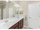 Bright bathroom with double sinks, a large mirror, dark wood cabinets, and neutral tile flooring at 20231 Lagente Cir, Venice, FL 34293