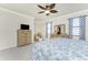 Bright bedroom with a TV, a sitting area, and a bed with floral bedding and blue patterned curtains at 20231 Lagente Cir, Venice, FL 34293