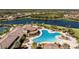 Aerial view of community pool, sun loungers, and clubhouse with nearby lake and foliage at 20231 Lagente Cir, Venice, FL 34293