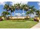 Stone community entrance featuring palm trees, flowering plants, and manicured green lawns at 20279 Lagente Cir, Venice, FL 34293