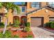 Inviting home exterior with arched entryway, lush garden, and beautiful brick driveway at 20279 Lagente Cir, Venice, FL 34293
