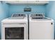 Modern laundry room with side-by-side washer and dryer, complemented by bright blue walls at 20279 Lagente Cir, Venice, FL 34293