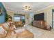 Bright living room with tile floors, leather sofa, flat-screen TV, and sliding glass doors to a patio at 20279 Lagente Cir, Venice, FL 34293