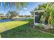 Manicured backyard featuring a screened-in patio and waterfront view at 235 Caddy Rd, Rotonda West, FL 33947