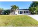 Charming single-story home with a well-manicured lawn, mature trees, and a bright blue front door at 235 Caddy Rd, Rotonda West, FL 33947
