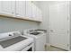 Well-lit laundry room features a washer, dryer, utility sink, and white cabinets at 25207 Spartina, Venice, FL 34293