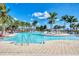 A resort-style swimming pool is surrounded by palm trees and lounge chairs under a clear blue sky, creating a serene oasis at 25207 Spartina, Venice, FL 34293