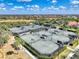 Aerial view of multiple tennis courts with well-maintained green surfaces, landscaping and nearby residential area at 25207 Spartina, Venice, FL 34293