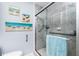 Stylish bathroom featuring a shower with a glass door and grab bars, and decorated with seaside themed wall art at 2955 N Beach Rd # D123, Englewood, FL 34223