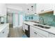 Open kitchen boasts white cabinets, stone countertops, stainless appliances, and adjacent dining and living rooms at 2955 N Beach Rd # D123, Englewood, FL 34223
