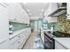 Galley kitchen features white cabinetry, stone countertops, colorful backsplash, and stainless steel appliances at 2955 N Beach Rd # D123, Englewood, FL 34223
