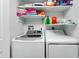 Bright laundry room featuring a washer, dryer and shelving with stacked towels and detergent supplies at 2955 N Beach Rd # D123, Englewood, FL 34223