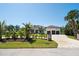 Front view of home highlighting three-car garage, circular driveway, lush landscaping, and inviting entrance at 425 Spaniards Rd, Placida, FL 33946