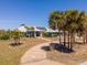 Aerial view of a single story home with solar panels, palm trees, a circular driveway, and ample green space at 50 Spyglass Aly, Placida, FL 33946