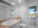 Bathroom with modern sink, toilet, mirror, and glass enclosed shower and pool view at 50 Spyglass Aly, Placida, FL 33946