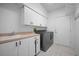 Well-lit laundry room featuring a modern washer and dryer, plenty of cabinet space, and tile flooring at 50 Spyglass Aly, Placida, FL 33946