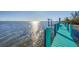 Wooden dock with blue posts extends into the water with sunlight glistening on the water at 6035 Manasota Key Rd, Englewood, FL 34223