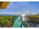 Dock on the water with beautiful sun shining on tranquil blue water, and lush green plants at 6035 Manasota Key Rd, Englewood, FL 34223