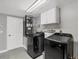 Well-equipped laundry room with modern black washer and dryer, cabinets, and utility sink at 6035 Manasota Key Rd, Englewood, FL 34223
