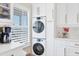 A utility room features a stacked washer and dryer, white cabinets with brass pulls, and a large window at 6040 Boca Grande Cswy # A2, Boca Grande, FL 33921