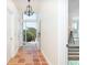 Hallway featuring terracotta tile flooring, chandelier, access to a bedroom and front entrance door at 62 Tarpon Way, Placida, FL 33946