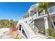 Coastal style home featuring a dual staircase leading to a covered porch, surrounded by tropical landscaping at 62 Tarpon Way, Placida, FL 33946