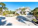 Two-story coastal home with white exterior, palm trees, large sandy yard and stairway to the front door at 62 Tarpon Way, Placida, FL 33946