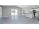Open-concept living space with high ceilings, gray wood-look floors, flowing into the kitchen with island at 6602 David Blvd, Port Charlotte, FL 33981