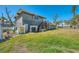 Back exterior showing a home with mature trees, a yard, stairs, and an elevated deck at 698 & West W Perry St, Englewood, FL 34223
