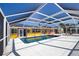 Screened-in pool featuring a tile deck is surrounded by the yellow and orange home at 741 W Perry St, Englewood, FL 34223