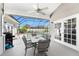 Screened-in patio features a ceiling fan, outdoor dining set, and access to a sparkling pool for comfortable outdoor living at 820 Bayshore Dr, Englewood, FL 34223