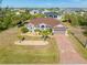 Aerial view of a single-story home with a well-manicured lawn, landscaping, and a long driveway with decorative palm trees at 8251 Arlewood Cir, Port Charlotte, FL 33981