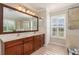 Elegant bathroom with a double sink vanity, large mirror, walk-in shower, and plantation shutters for natural light at 8251 Arlewood Cir, Port Charlotte, FL 33981